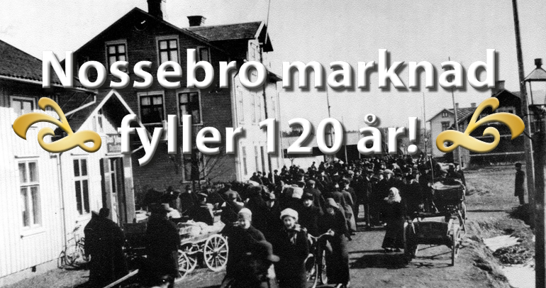 Den svartvita bilden visar Nossebro längs Storgatan runt sekelskiftet 1900. Många människor går mitt i gatan. 